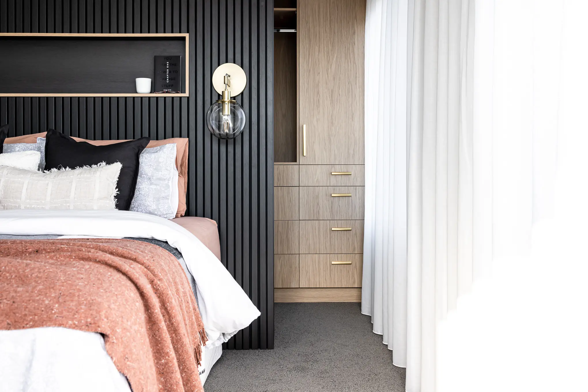 Elegant bedroom design in Hobart showcasing a modern bedside light, textured wall, and warm wood accents, crafted by a local interior designer.