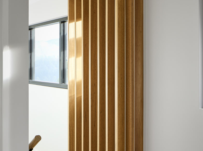 Interior designer in Hobart showcases a contemporary wooden slatted wall feature, enhancing natural light and modern aesthetics in a space designed by Cove Interior Design.