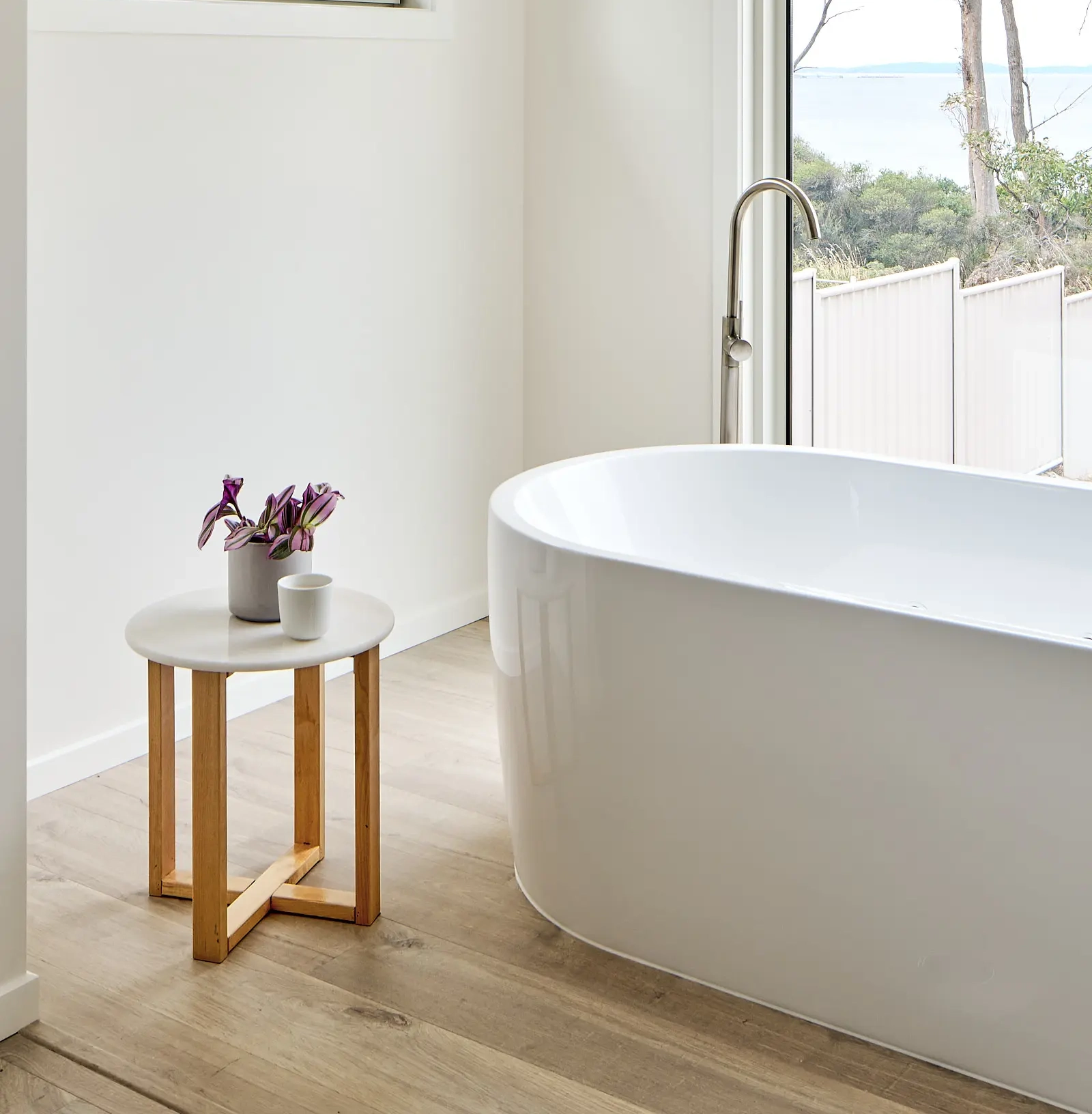 Minimalist and serene bathroom design by an interior designer in Hobart, featuring a freestanding tub with scenic views and subtle decor accents.